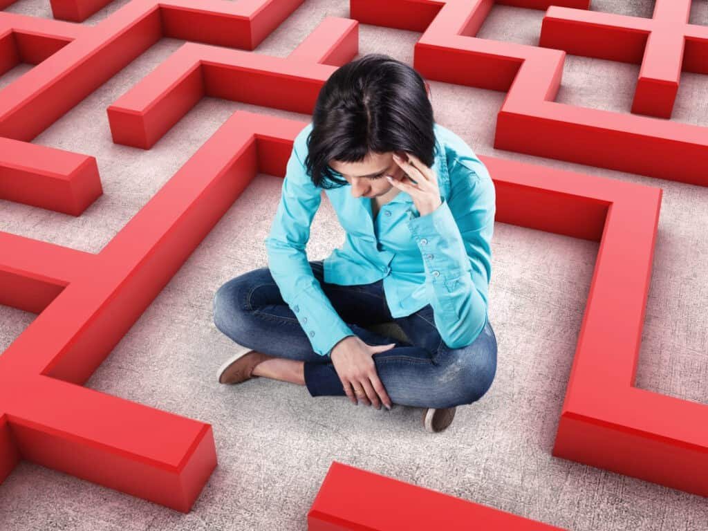 Sad girl sits in a labyrinth with red walls