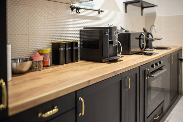 Coffee Station Goals: How to Create a Café Vibe at Home 1 Modern kitchen with black cabinets, wooden countertop, coffee machine, toaster, electric kettle, and various containers neatly arranged––perfect for creating a cozy café vibe at home.