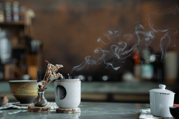 A steaming mug, a small vase with dried flowers, and a lidded jar sit on a table&mdash;simple touches that invite quick mindfulness even on a busy day. The blurred kitchen background adds to the calming scene.
