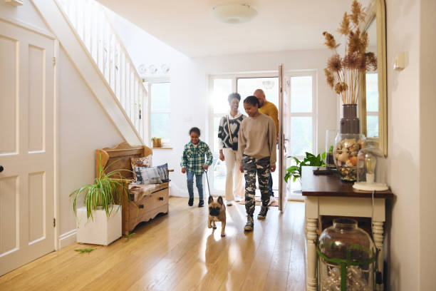 A family of four and a small dog enter a bright, tidy hallway with wooden floors, houseplants, and decorative items—a true pet-friendly sanctuary offering mental peace.