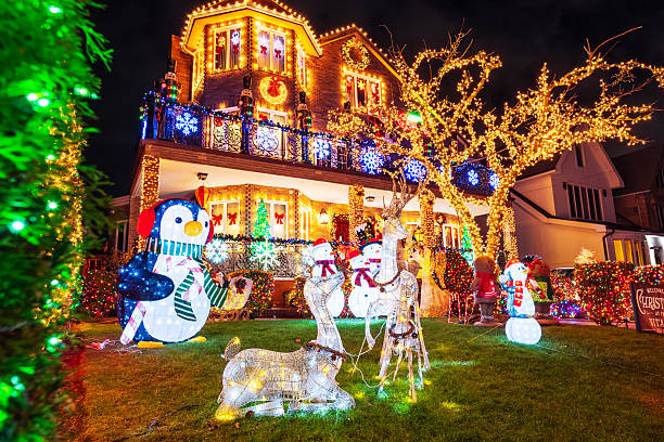 A house decorated with bright Christmas lights, light-up figures including a penguin and snowmen, and illuminated reindeer on the front lawn at night creates a festive display of vibrant seasonal decor.